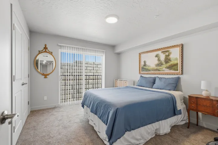 Recessed lighting, light gray walls, white trim, sliding glass door, and neutral-toned carpeting