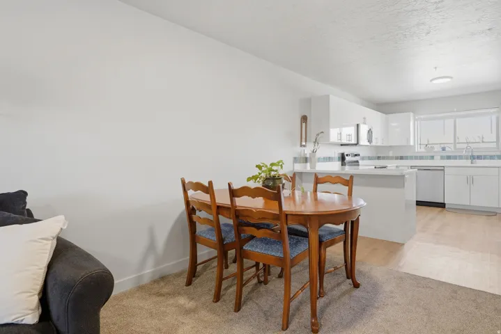 Open concept kitchen with white cabinetry, stainless steel appliances, and wood-finish flooring