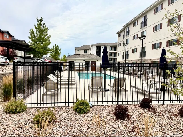 Outdoor swimming pool with surrounding fence, adjacent patio, and stone landscaping
