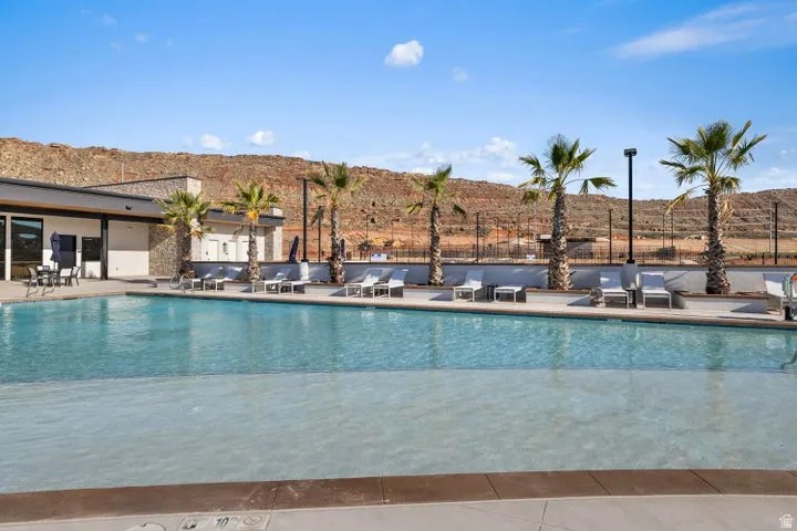 Resort-style pool area featuring a large swimming pool, surrounding patio, and a backdrop of natural rock formations