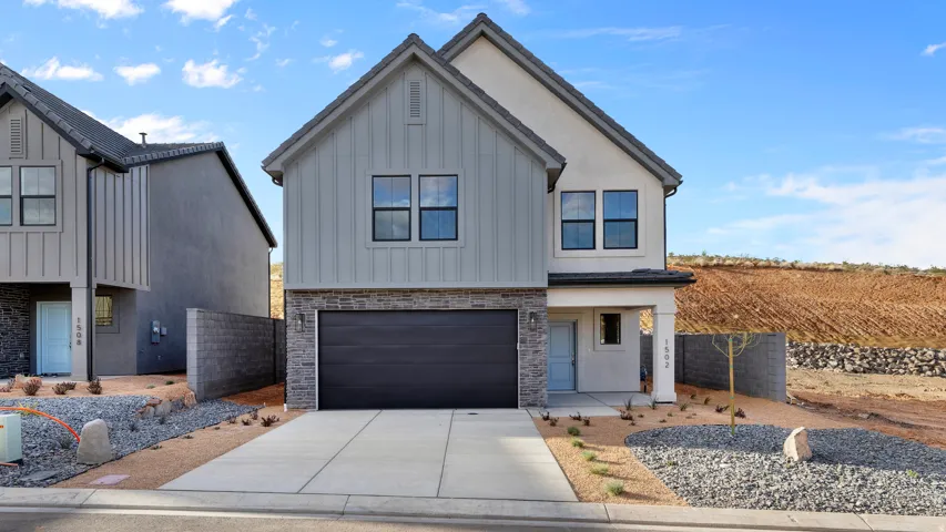 Contemporary exterior with board and batten and stucco siding, featuring a two-car garage, covered entry, and xeriscaping