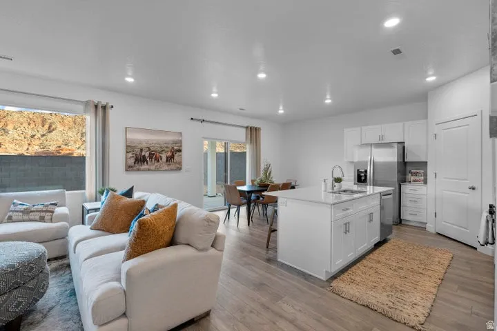 Open-concept living area with wood-finish flooring, recessed lighting, and a kitchen island with seating
