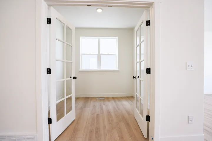 Office/den with double french doors adjacent to kitchen.