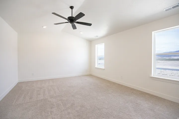Spacious primary bedroom with vaulted ceiling, and ceiling fan.