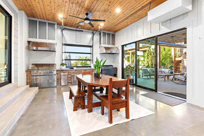 Outdoor kitchen featuring a built-in grill, white subway tile backsplash, and a wood-paneled ceiling