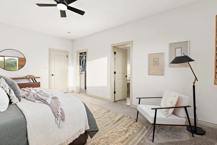 Textured carpeting, white walls, black ceiling fan with integrated lighting, and a paneled interior door