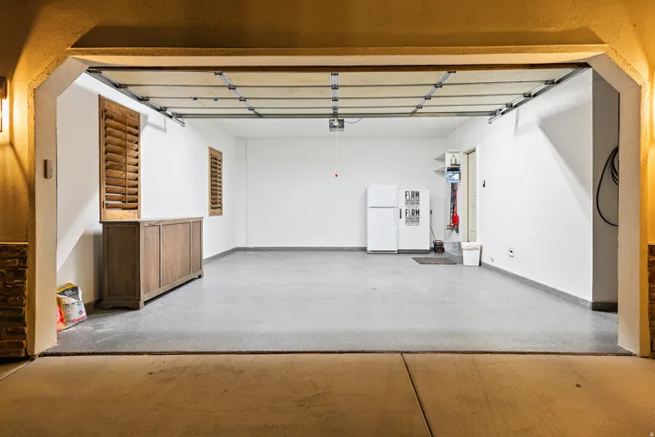 Spacious garage featuring a finished floor, white painted walls, and built-in shelving