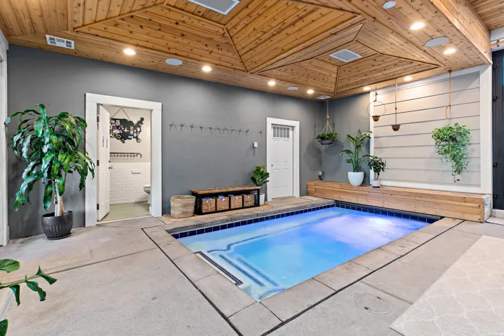 Indoor plunge pool with blue tile surround, concrete flooring, and a wood plank ceiling with recessed lighting
