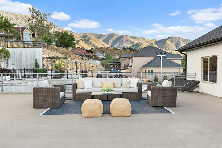 Expansive outdoor patio with concrete flooring, mountain backdrop, and metal railings