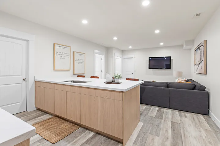 Open concept living space featuring wood-finish flooring, recessed lighting, a kitchen island with light wood-finish cabinetry, and a built-in stainless steel sink