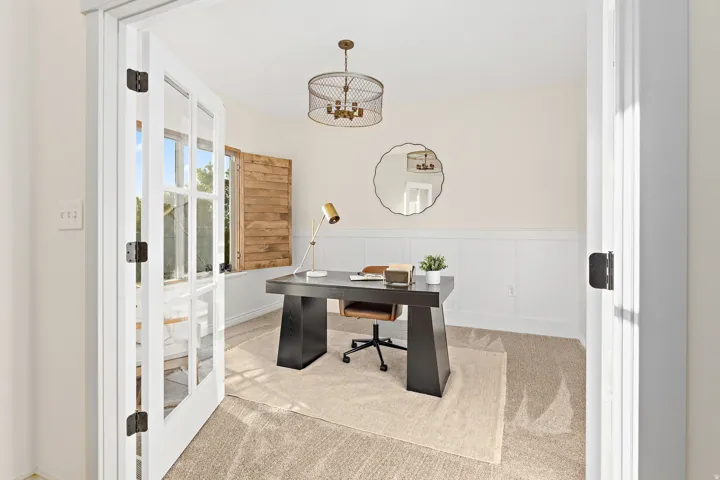 French doors opening to a space with wainscoting and natural wood window shutters