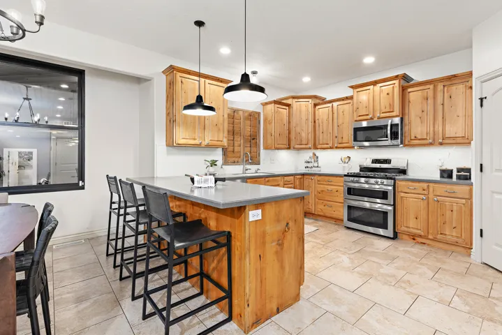 Kitchen featuring wood cabinetry, stainless steel appliances, a center island with countertop seating, recessed lighting, and tile flooring