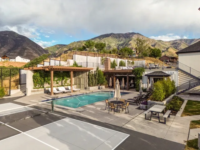 Outdoor swimming pool with integrated spa and lounge area, adjacent to a hard surface sports court
