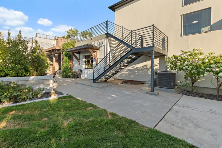 Exterior staircase with metal railings leading to an upper-level deck