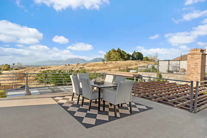 Expansive outdoor terrace with concrete flooring, metal railing, and a brick chimney structure