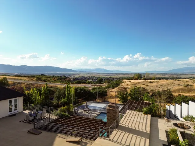 Expansive concrete patio with metal railing, an outdoor fire pit, and a swimming pool with cover