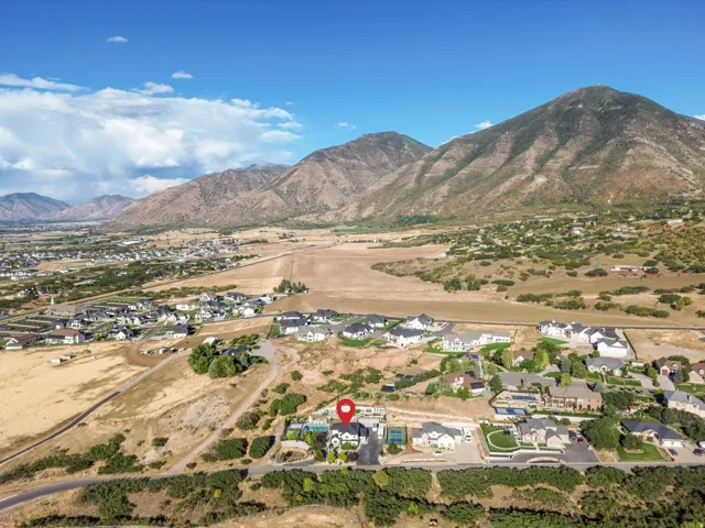 Expansive residential property set against a mountainous backdrop, featuring a swimming pool, tennis court, and mature landscaping