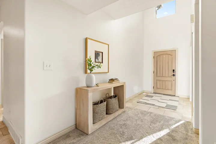 Vaulted ceiling entry with a wood-panel arched door, transom window, and tile flooring