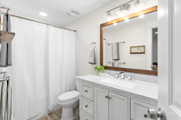White vanity with shaker-style cabinetry, a white countertop, and an integrated rectangular sink