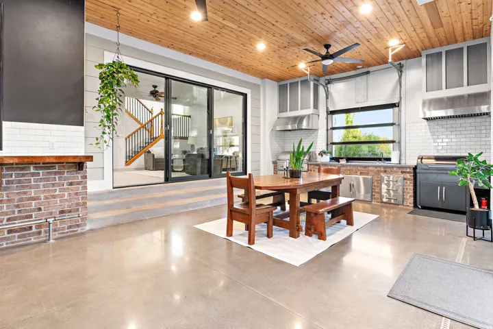 Wood-paneled ceiling, concrete flooring, exposed brick accents, modern ceiling fan, and large sliding glass doors
