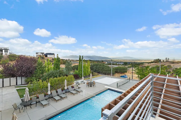 Outdoor swimming pool, paved patio, trellis structure, landscaped perimeter, and hardscaped recreational court