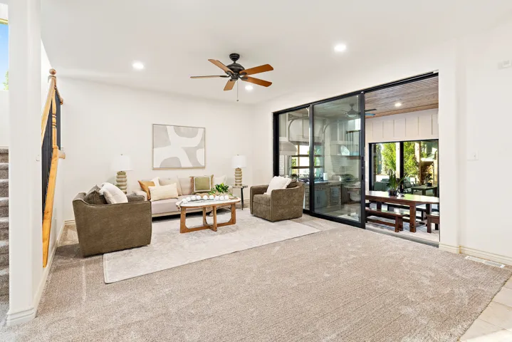 Spacious living area featuring neutral carpeting, recessed lighting, and a ceiling fan