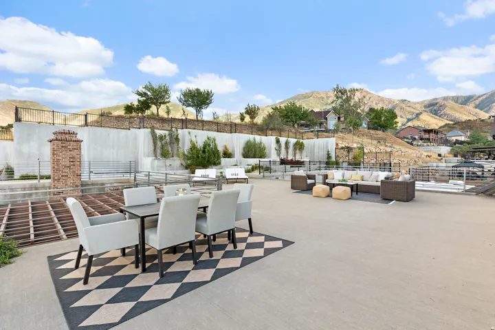 Expansive outdoor patio with mountain backdrop, featuring a brick-clad pillar and metal railings