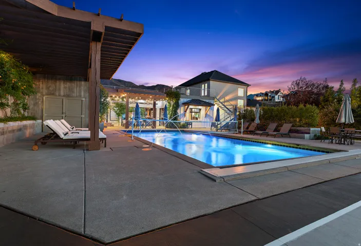 Rectangular swimming pool surrounded by concrete decking, featuring an adjacent pergola structure
