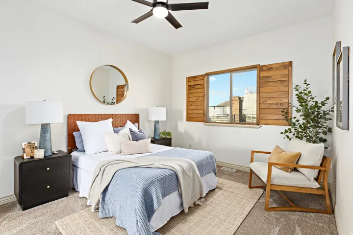 Vaulted ceiling with a ceiling fan, recessed window with wood shutters, and neutral carpet flooring