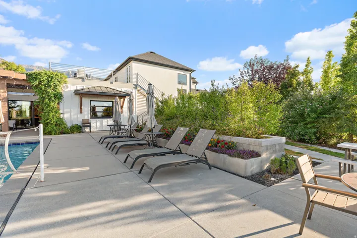 Outdoor hardscaping with a built-in pool, adjacent lounge area, and raised planters