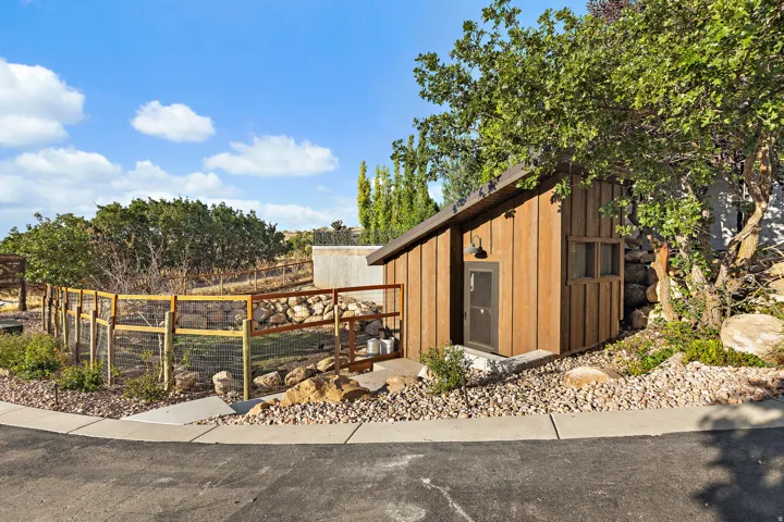 Chicken Coop-Outbuilding with wood siding, a dark sloped roof, and an exterior light fixture