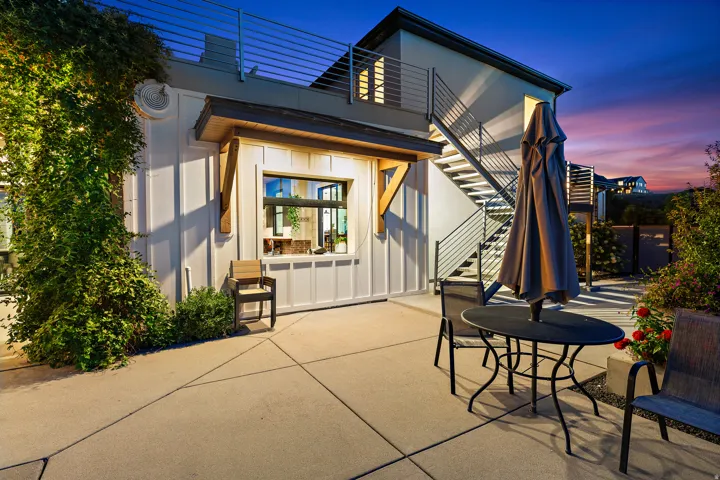 Exterior patio with concrete paving, a built-in serving window, and an external staircase featuring metal railings