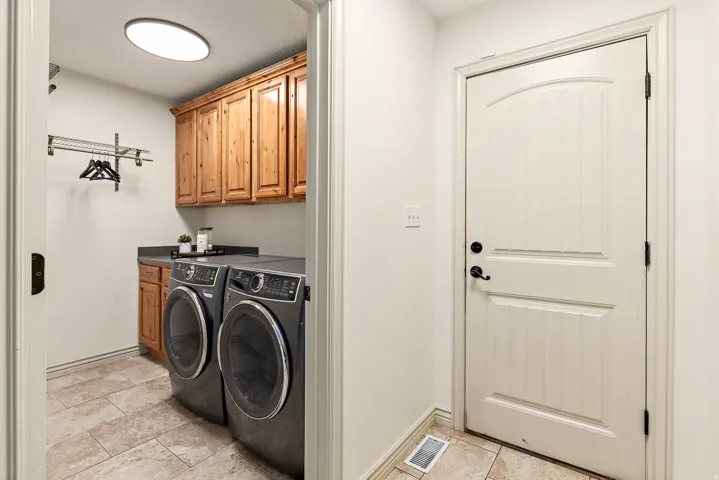 Laundry area featuring wood cabinetry, dark countertop, and tile flooring