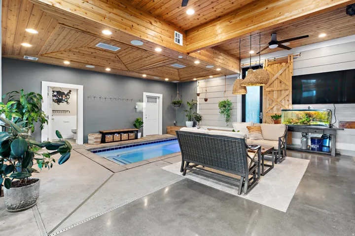Indoor pool with concrete surround, wood plank ceiling, exposed wood beams, ceiling fan, and recessed lighting