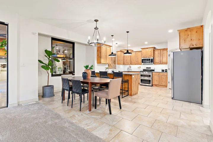 Spacious kitchen and dining area featuring natural wood cabinetry, stainless steel appliances, and a central island with pendant lighting