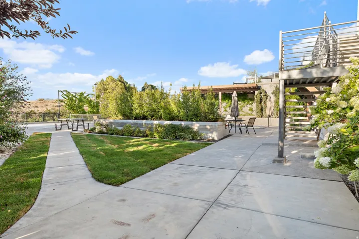 Expansive concrete patio with integrated landscaping, a raised planting bed, and a metal staircase with railing