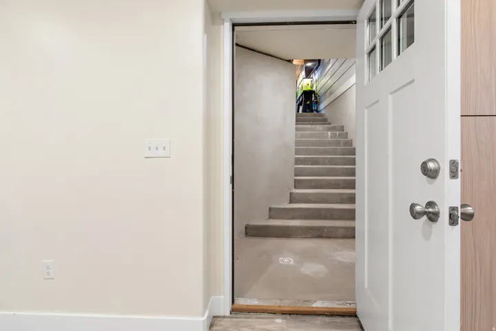 AD Private Entrance. White paneled door with glass inserts, concrete staircase, and neutral wall paint