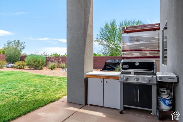 Outdoor patio featuring a built-in cabinet with wood-finish countertop, a stainless steel grill, and a concrete paver surface