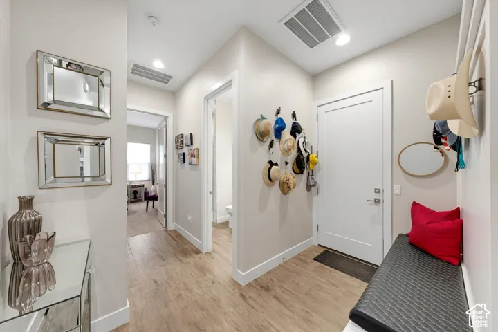 Wood-finish flooring, recessed lighting, and white trim accents define this interior hallway