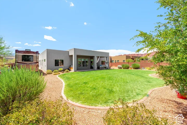 Expansive lawn with a defined border, covered patio, and desert landscaping
