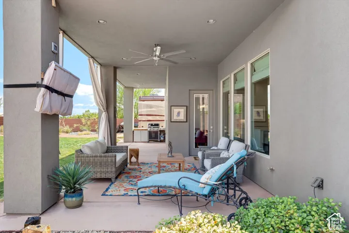 Covered patio with recessed lighting, ceiling fan, multiple windows, and an outdoor kitchen with built-in cabinetry
