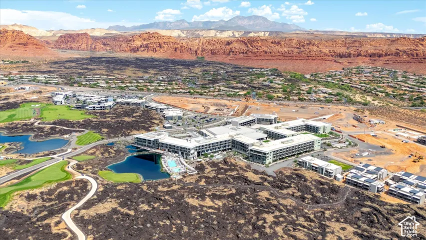Expansive property featuring a large resort complex, multiple water features, manicured golf course, and surrounding red rock landscape