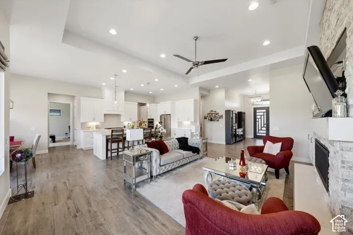 Open-concept living area featuring wood-finish flooring, a stone-clad fireplace, and recessed lighting