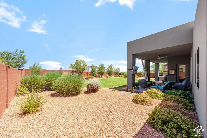 Expansive backyard featuring a covered patio, manicured lawn, and low-maintenance landscaping
