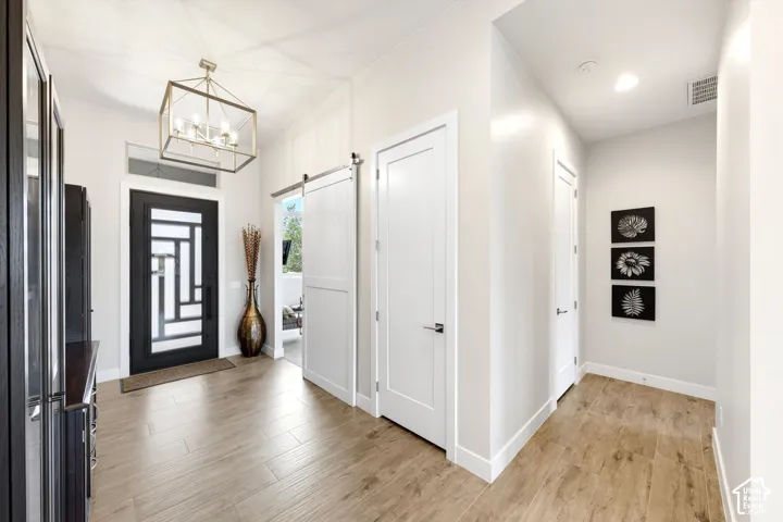 Entryway with wood-finish flooring, a decorative glass-paneled entry door, and a gold-finish geometric chandelier
