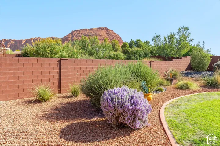 Enclosed backyard with a block wall, natural landscaping, gravel ground cover, and a manicured lawn area