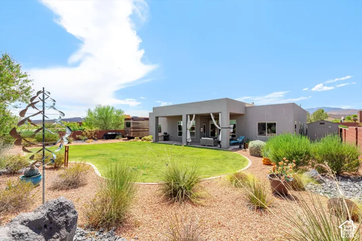 Expansive backyard featuring a manicured lawn, established landscaping, and a covered patio structure