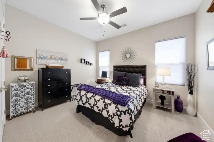 Angled ceiling, recessed lighting, ceiling fan with light fixture, two windows with blinds, and light-toned carpet flooring