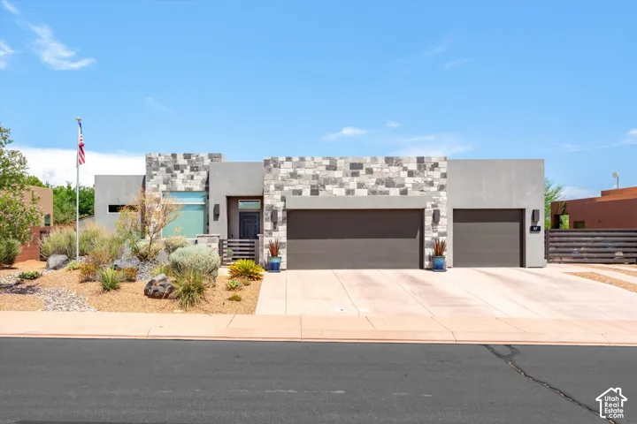 Modern exterior featuring stacked stone accents, stucco finish, a covered entry, and a two-car garage with contemporary doors