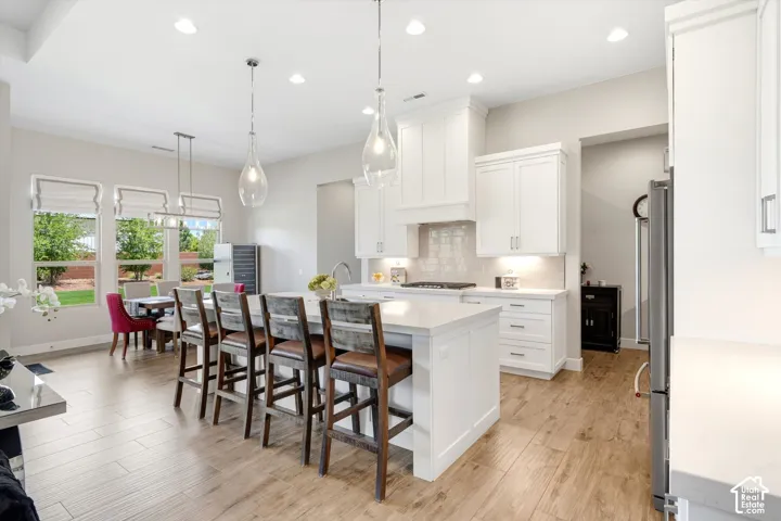 White shaker cabinetry with under-cabinet lighting, stainless steel appliances, and a tile backsplash